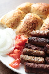 A balkan traditional meatball dish cevapi, cevapcici  on wooden table in close-up	