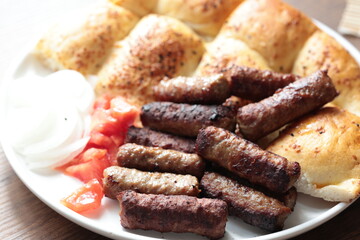 A balkan traditional meatball dish cevapi, cevapcici  on wooden table in close-up	