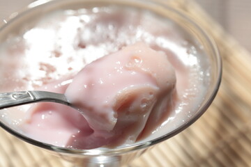 Strawberry pink pudding in glass mug on wooden table close up
