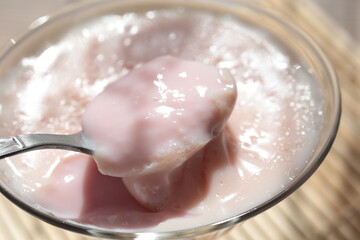 Strawberry pink pudding in glass mug on wooden table close up