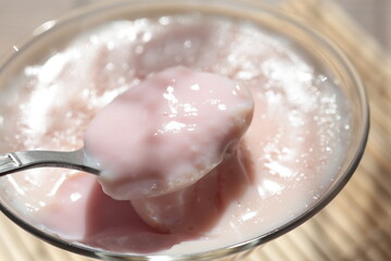 Strawberry pink pudding in glass mug on wooden table close up