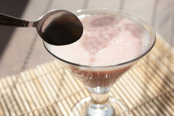 Strawberry pink pudding in glass mug on wooden table close up