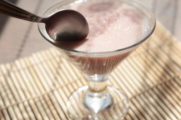 Strawberry pink pudding in glass mug on wooden table close up