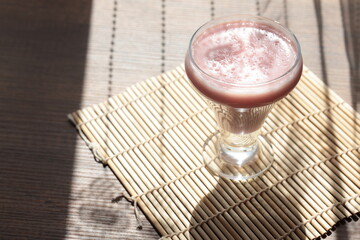 Strawberry pink pudding in glass mug on wooden table close up