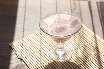Strawberry pink pudding in glass mug on wooden table close up