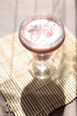 Strawberry pink pudding in glass mug on wooden table close up