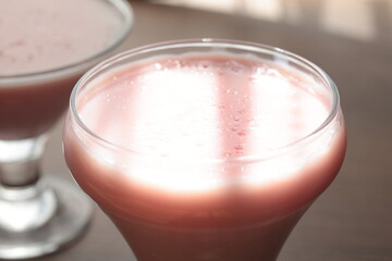 Strawberry pink pudding in glass mug on wooden table close up