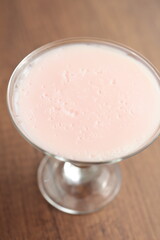 Strawberry pink pudding in glass mug on wooden table close up