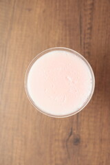 Strawberry pink pudding in glass mug on wooden table close up