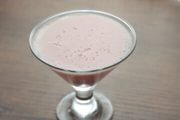Strawberry pink pudding in glass mug on wooden table close up