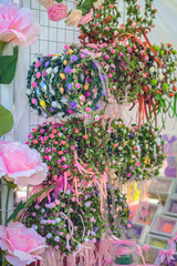 Colorful floral wreaths for hair, handmade decor hanging on market stand in daylight. Traditional festive decoration during annual rose festival in Bulgaria