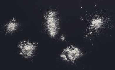 White flour splash spot on black background. Top view on blackboard. Baking concept, cooking dough...