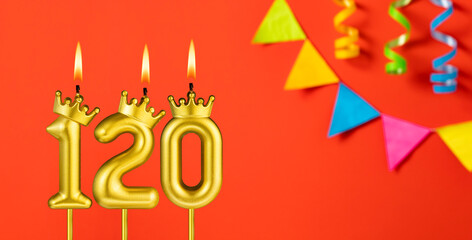 Number 120 birthday candle on an orange background with pennants