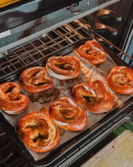 Golden Brown Soft Pretzels Baking in Home Oven on Parchment Lined Tray, Fresh Homemade Snack or Appetizer, Traditional Baked Goods with Salt Crust, Closeup Kitchen Scene