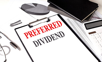 Preferred dividend text on clipboard with charts, calculator, notebooks and pen on white desk