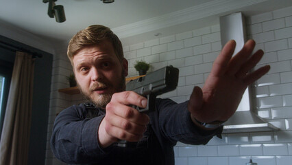Uniformed man carefully aims a handgun with one hand while gesturing to stop with the other,...