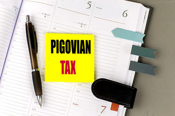 Pigovian tax text on yellow sticky note placed on planner with pen and bookmarks
