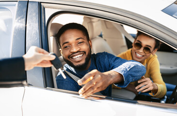 This image depicts a happy couple receiving the keys to their new car from a dealership...