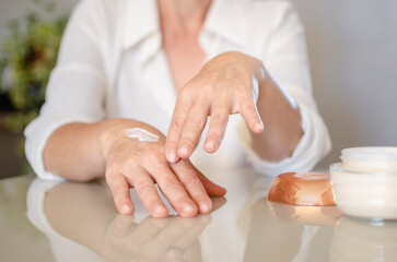 middle aged woman applying cream on her hands