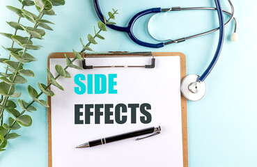 Side effects text on clipboard with pen, stethoscope and eucalyptus on blue background