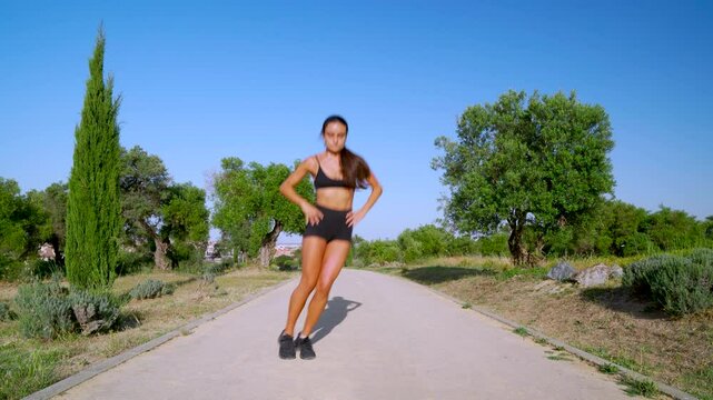 Mujer joven deportista haciendo ejercicios en el parque un  d&iacute;a soleado con cielo azul.