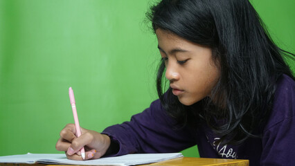 Girl is writing in book, making notes on a diary, green color background