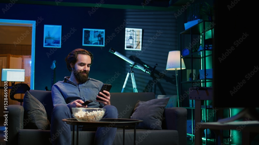 Aufkleber smiling person on couch picking movie on streaming service using remote and texting on mobile phone.
