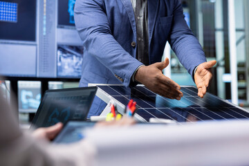 Investors examine solar panel surface, discussing design efficiency with factory management...