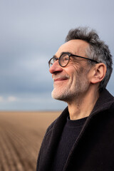 portrait of joyful agronomist on left side of frame with clean background of fields
