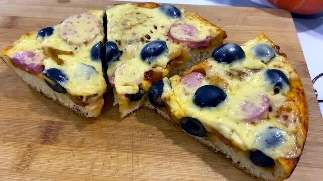 Pizza cooking process, homemade pizza slices with melted cheese and sausage. Pizza preparation in kitchen, close-up view. Concept make homemade pizza with simple delicious toppings. Slow motion video
