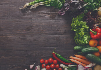 Left side border of fresh organic vegetables on wood background. Healthy natural food on rustic...