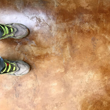 Brown Polished Screed Flooring: Modern design, angled view of feet in casual shoes. High-res screeding floor stain. Interiors, architecture.