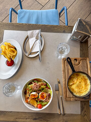 A vibrant brunch spread featuring a fresh salad, cheesy omelette, and golden fries with ketchup, set in a cozy eatery.