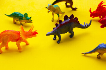 Plastic dinosaur toys on yellow background