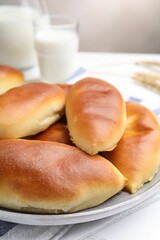 Tasty baked patties and spikelets on white wooden table against grey background, closeup