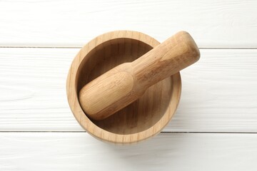 Mortar and pestle on white wooden table, top view