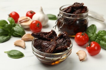 Delicious sun dried tomatoes, fresh vegetables, basil and garlic on white table, closeup