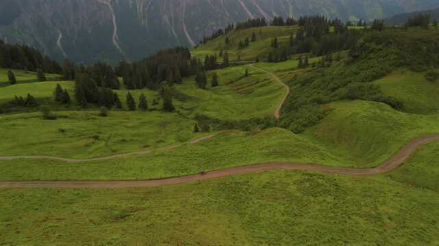Cyclist on gravel road amidst stunning alpine scenery of Fellhorn and Kanzelwand in Germanys Bavarian Alps. Aerial view of summer adventure with green mountains, trails, and breathtaking panoramas. 