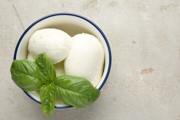 Tasty mozzarella cheese and basil on light table, top view. Space for text