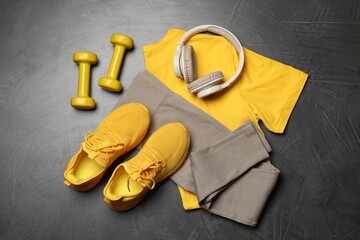 Sportswear, sneakers, dumbbells and headphones on grey background, flat lay