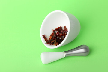 Mortar and pestle with spices on green background