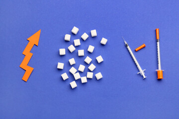Sugar cubes with syringes for insulin injection and arrow directed upwards on blue background