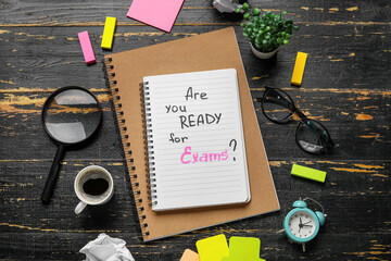 Notebooks with question ARE YOU READY FOR EXAM?, cup of coffee and magnifier on black wooden...