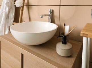 Sink bowl with bath accessories on table in bathroom