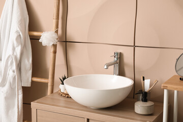 Sink bowl with bath accessories on table in bathroom