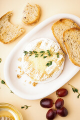 plate of tasty baked Camembert cheese with bread on yellow background