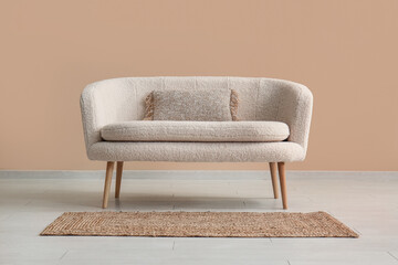 Cozy white sofa with pillow and carpet near beige wall