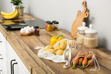 Mesh bags with different fresh vegetables on counter in kitchen