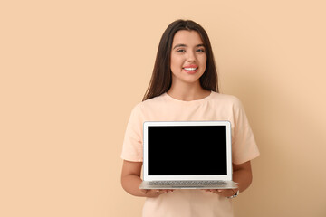Naklejka premium Happy young female programmer with laptop on beige background