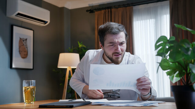Concerned man analyzing financial charts at desk